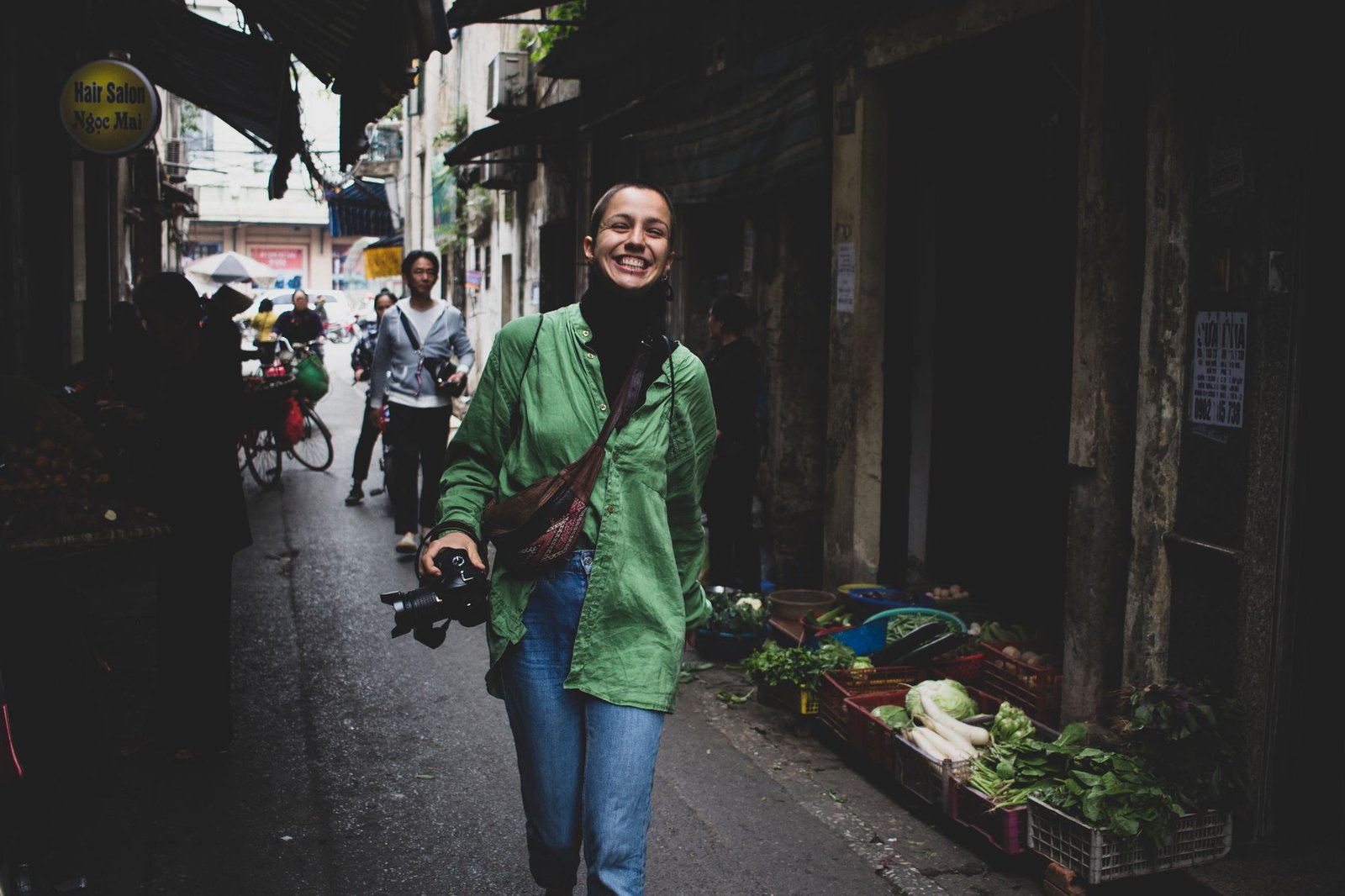 A cheerful woman walks through a bustling street market in Hanoi, Vietnam.