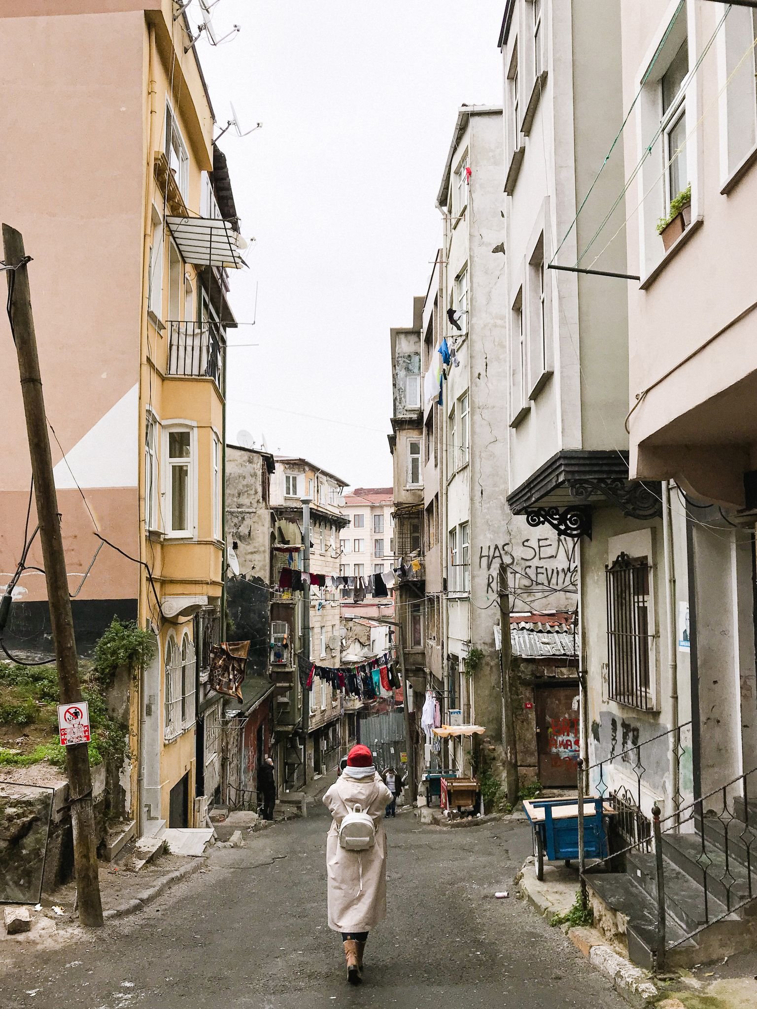 A person walks through a narrow alley lined with historic buildings and vibrant street life.