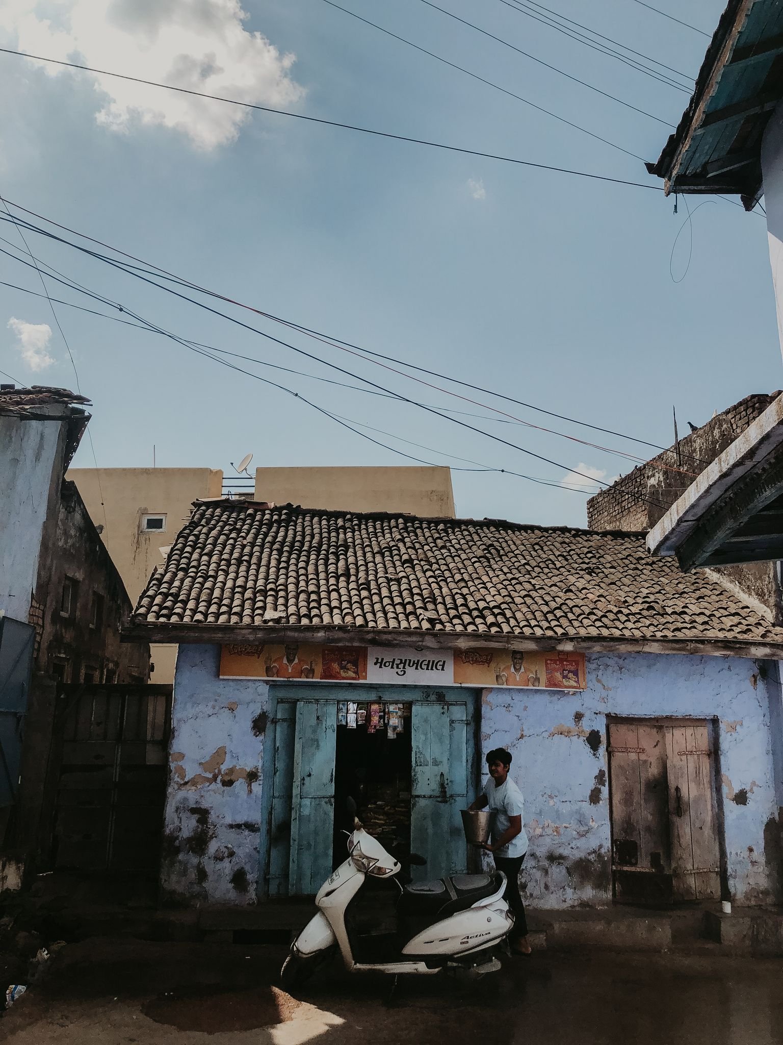 Outdoor scene of a rustic building with a scooter and person, showcasing everyday life.