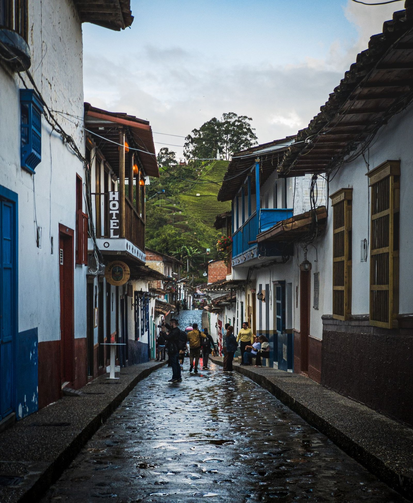 Vibrant cobblestone street scene with colorful buildings and people in a quaint town.