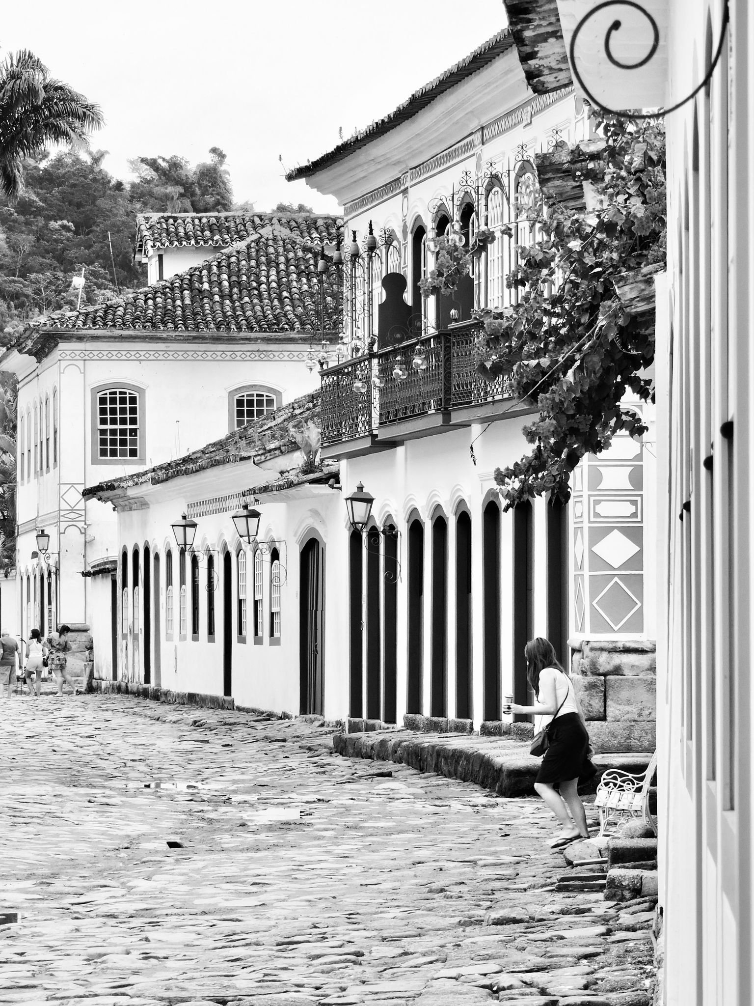 Black and white photo of a historic street with colonial architecture and cobblestone path.