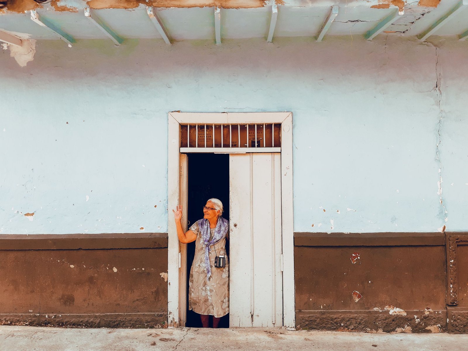 Elderly woman standing in a doorway of a rustic house in San Jerónimo, Colombia, capturing cultural essence.